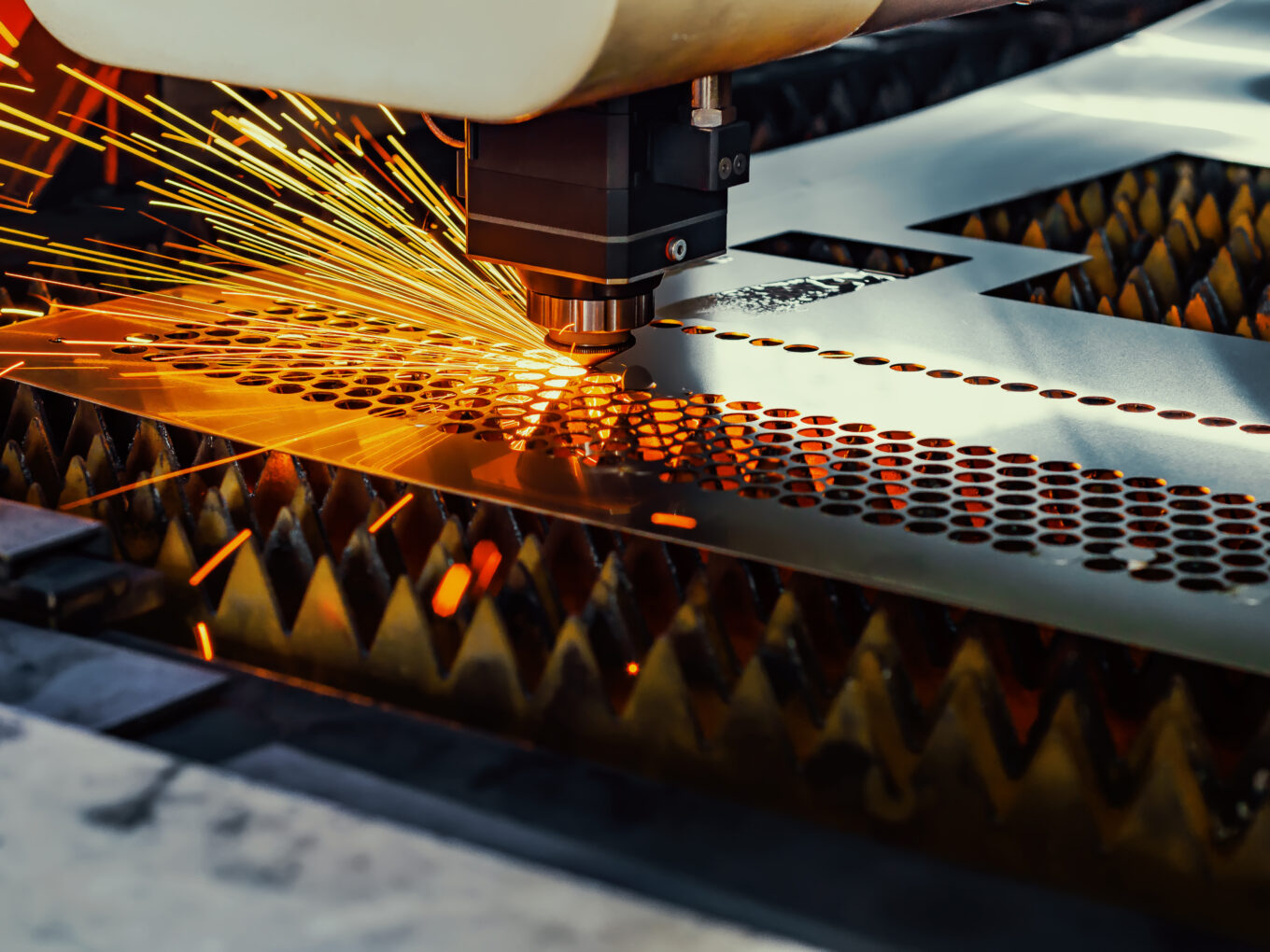 Laser cutting machine sparks perforated metal sheet creation.