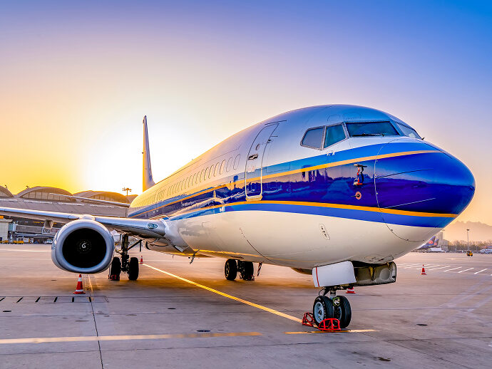 Airplane on tarmac at sunrise, airport terminal in background