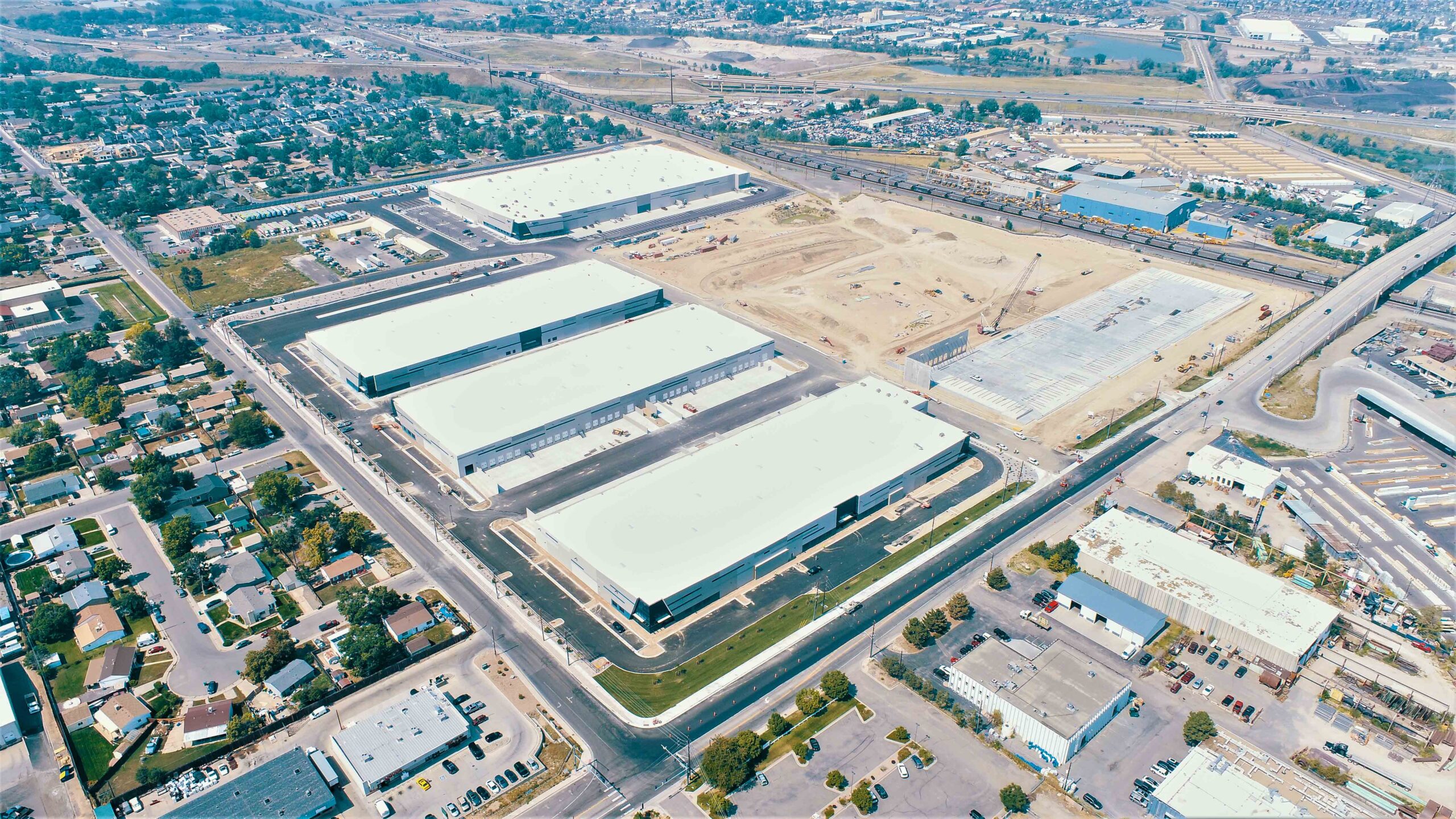 Aerial view of Pecos Logistics Park under construction, featuring large warehouses and surrounding residential area.