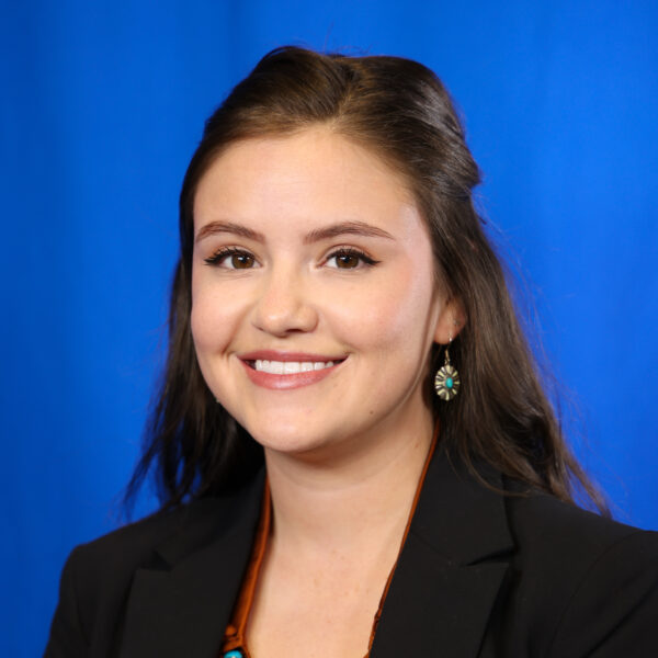 Updated-Frazier_Marki smiling in a formal outfit against a blue background